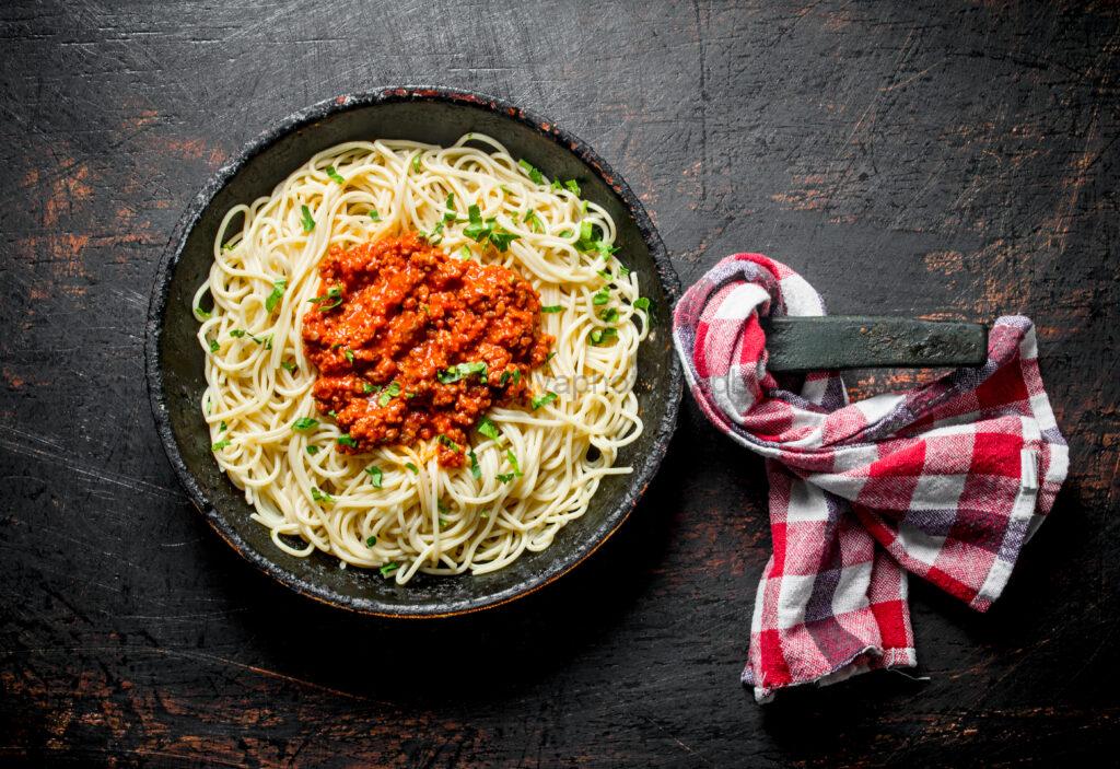 Spaghetti with Bolognese sauce in pan with napkin.